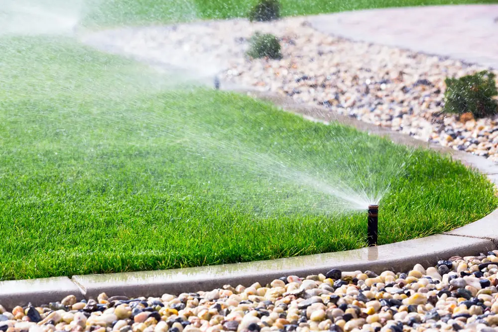 Modernes automatisches Bewässerungssystem mit Pop-up-Sprinklern auf saftigem grünem Rasen