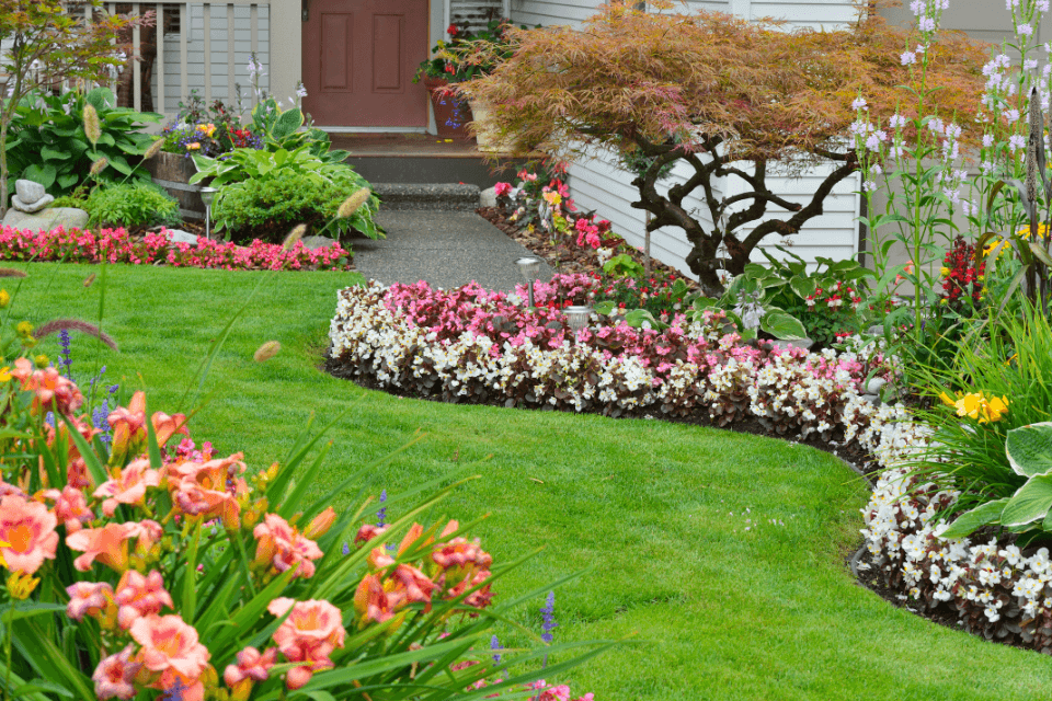 Wunderschön angelegter Garten mit farbenfrohen Blumenbeeten, saftigem Rasen und geschwungenem Gehweg